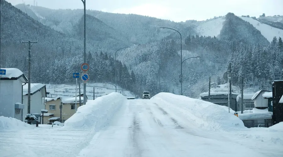 Remote rural Japanese scene in winter with snow-covered roads and hillsides